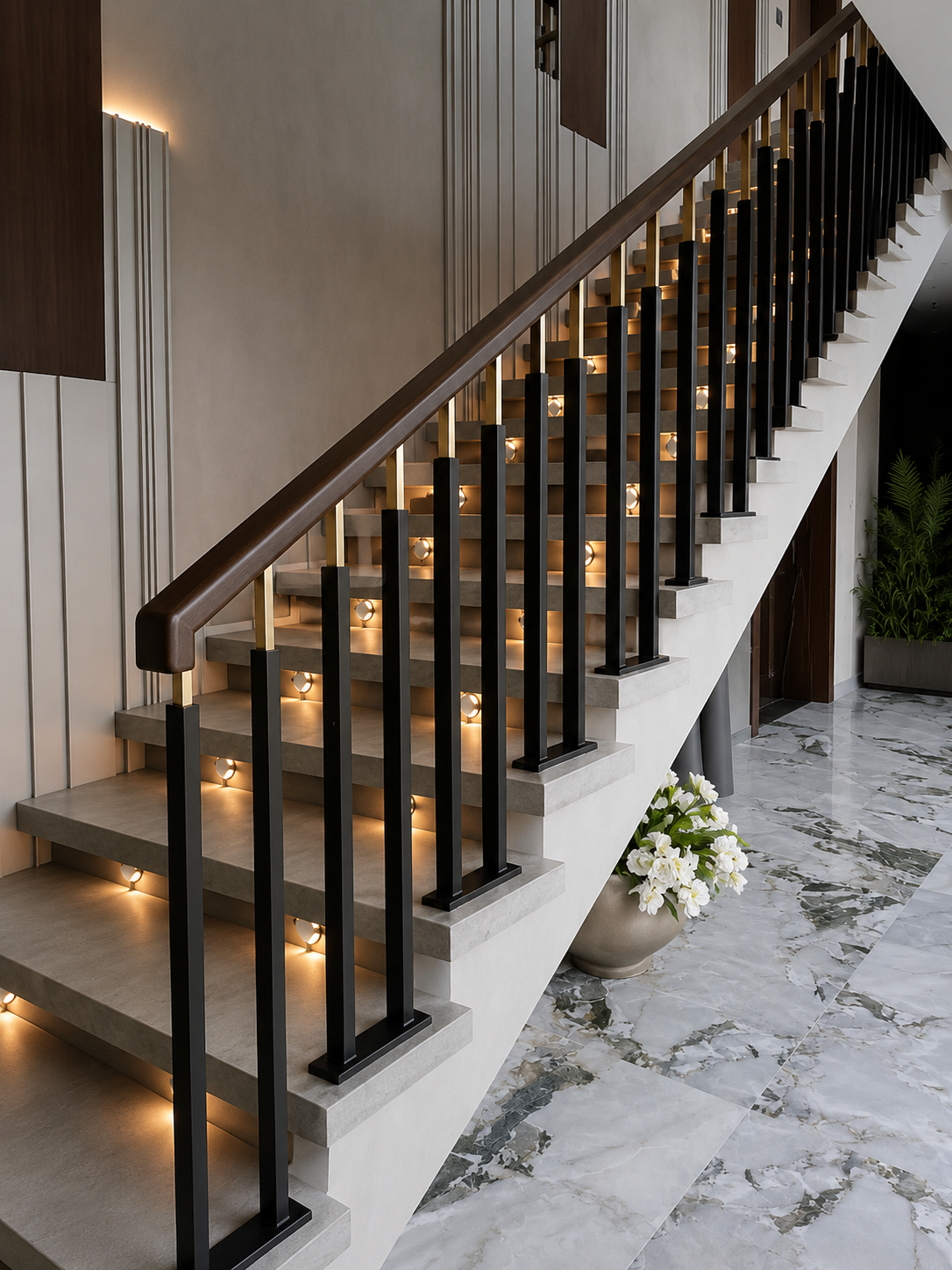 Modern black and Gold PVD stainless steel staircase railing with vertical balusters and dark wood handrail on an illuminated luxury staircase