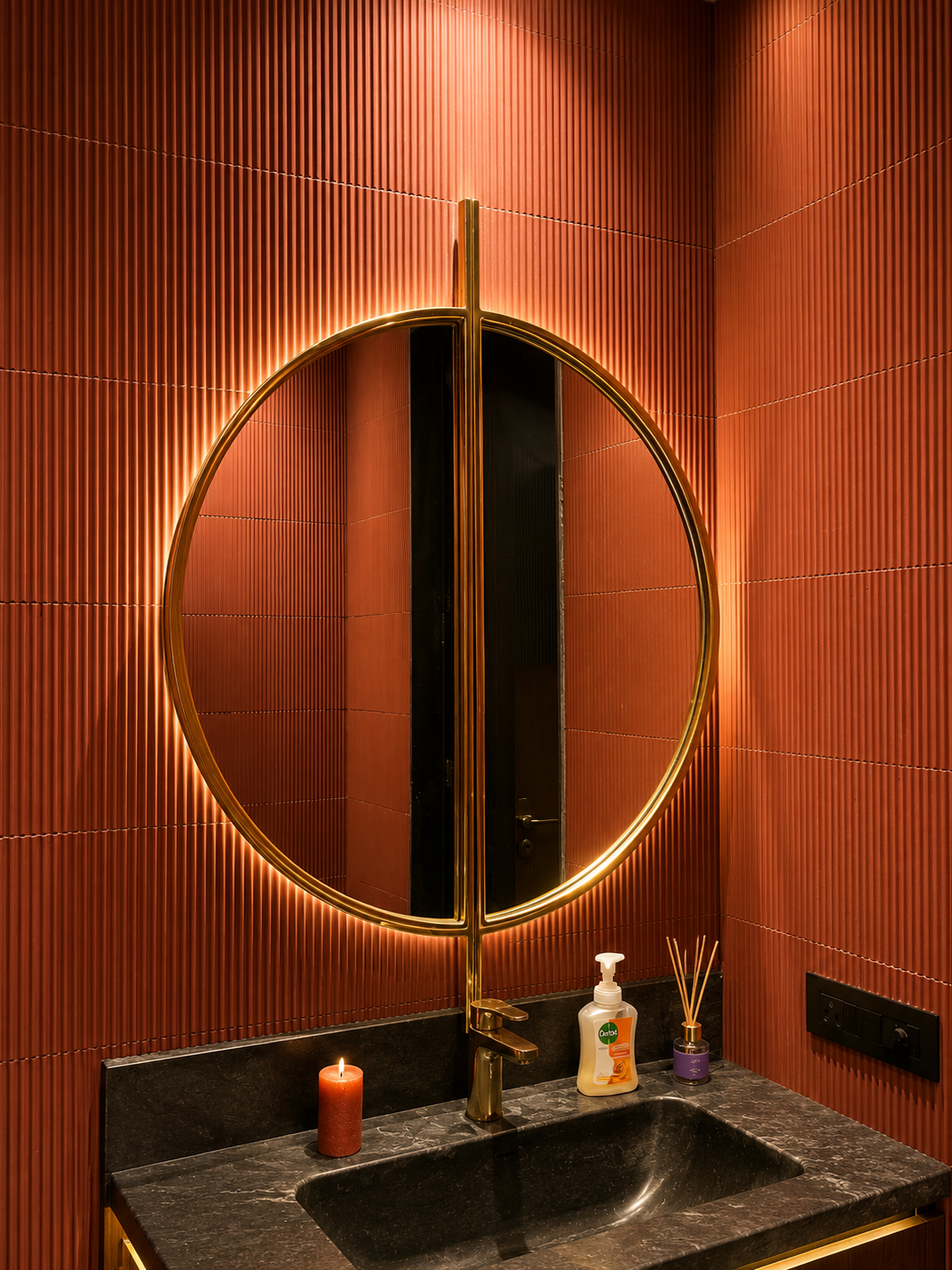 Solstice Axis circular mirror with Gold PVD central spine and warm backlighting in a luxury powder room