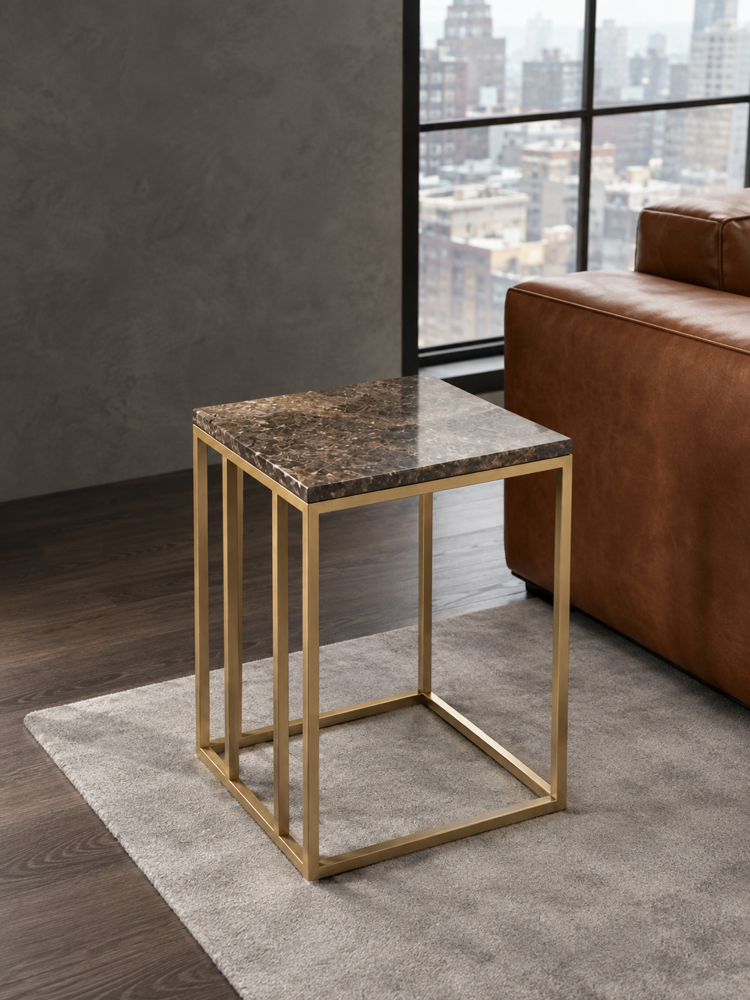 Emberline PVD gold corner table with square dark brown veined stone top beside a brown leather sofa