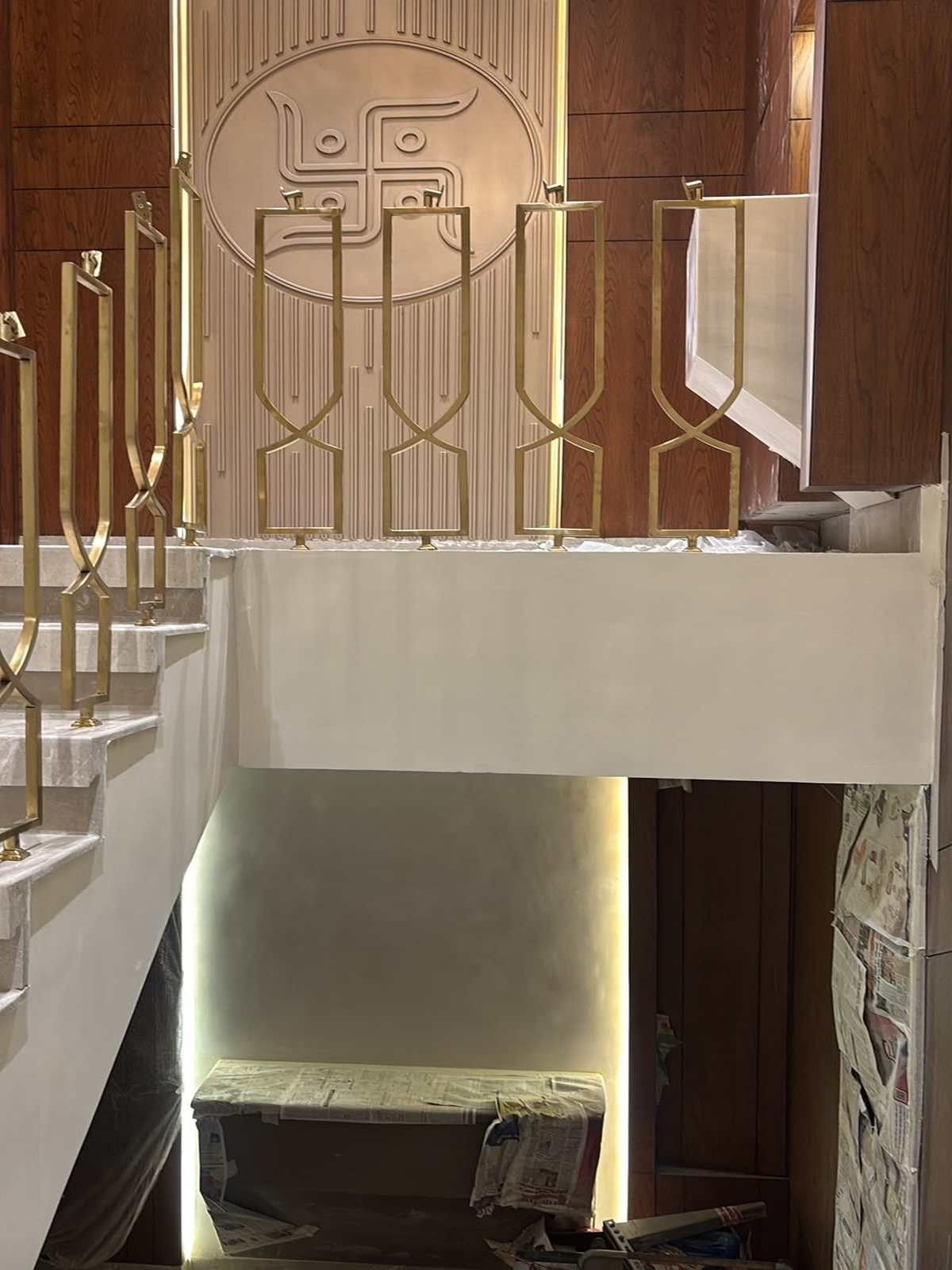 A bespoke staircase railing crafted with tall geometric gold-finish profiles and intersecting detailing.
