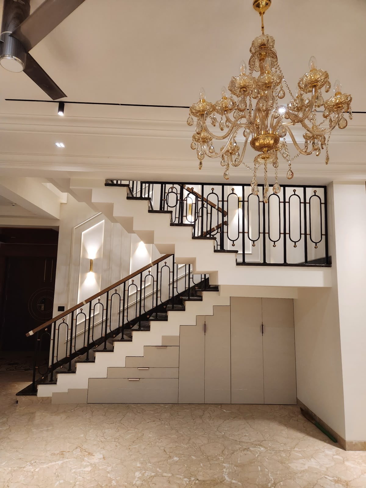 Custom staircase railing featuring slim black metal profiles, elongated geometric motifs and subtle gold accents.