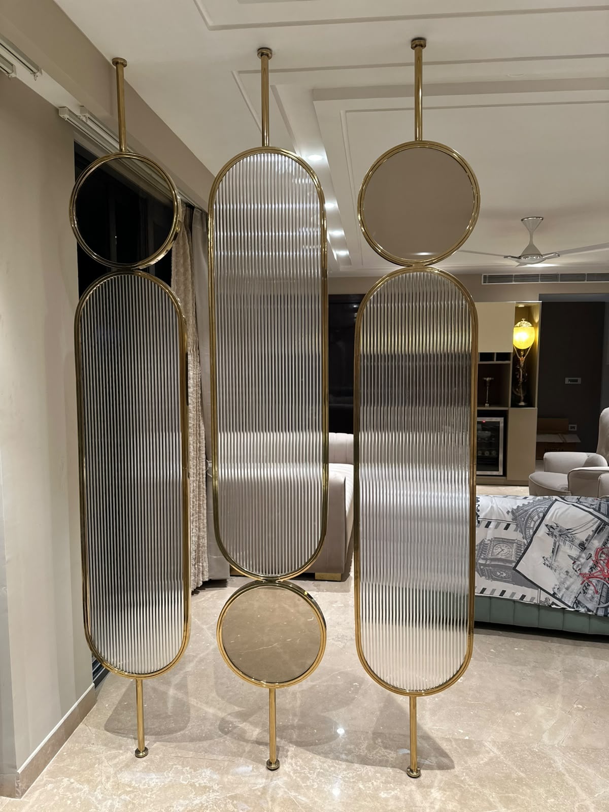 A sculptural three-panel divider featuring elongated rounded frames, circular accents and fluted glass inserts in a rich gold finish.